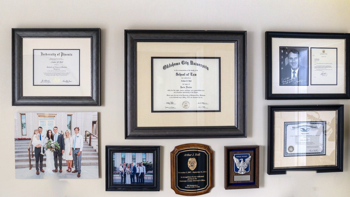 AJ Hall's office wall: University of Phoenix and Oklahoma City University School of Law diplomas, Eagle Scout award, Maricopa County Attorney's Office service plaque, and federal court admission